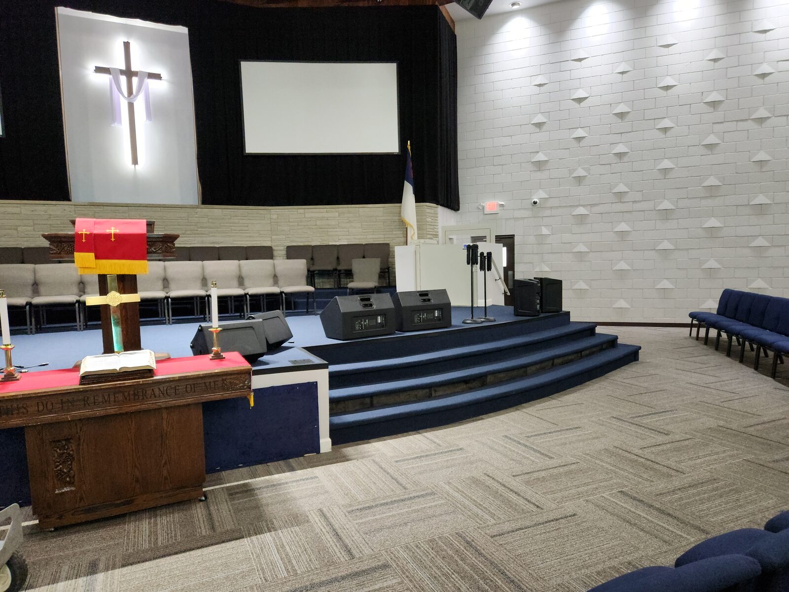 Mt. Gilead sanctuary stage from side angle — blue broadloom carpet, 3D acoustic wall panels, and projection screen — Nashville