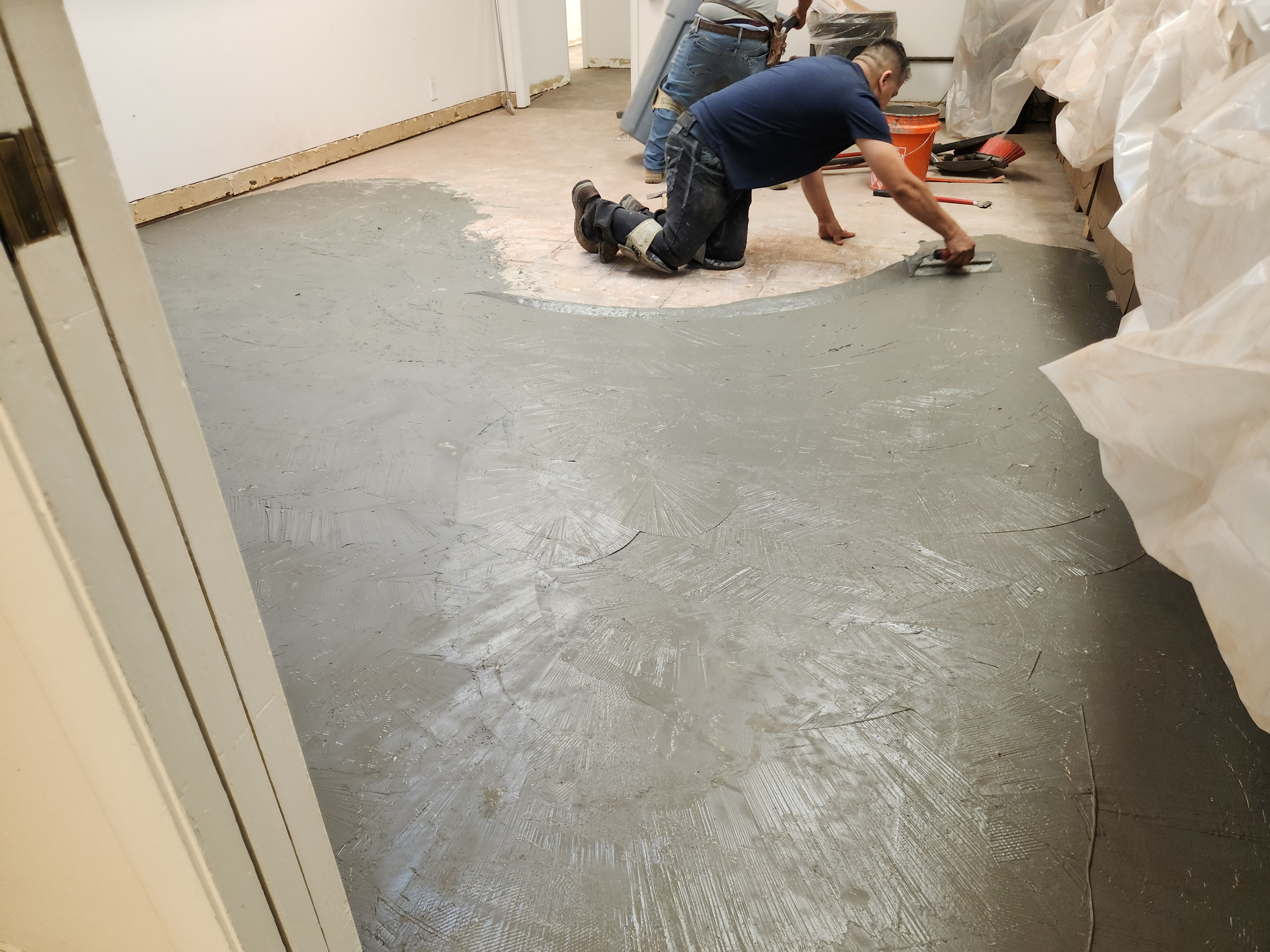 Self-leveling compound being troweled on concrete slab during commercial surface preparation — 180 Degree Floors, Nashville