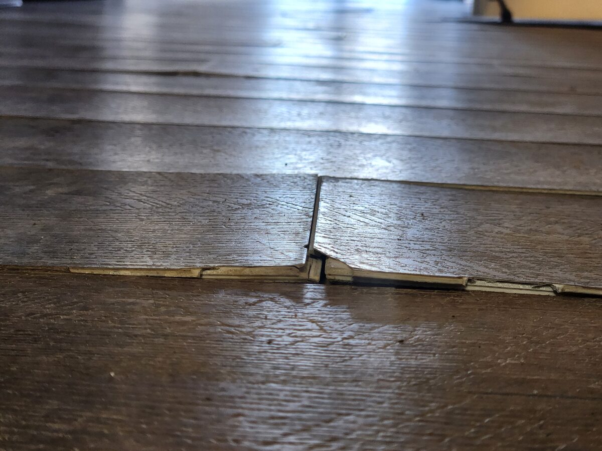 Water-damaged commercial flooring showing moisture-induced buckling and plank separation